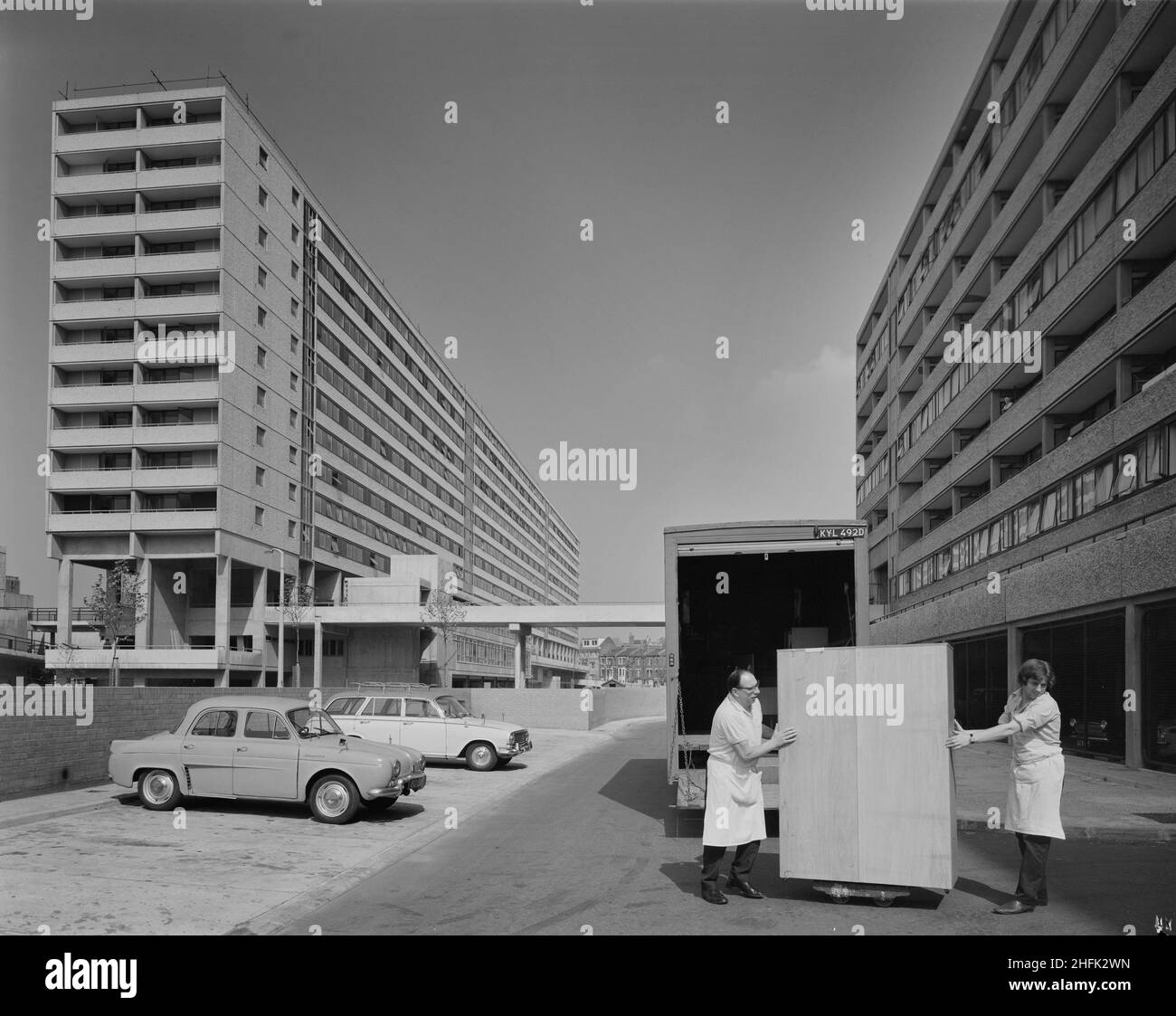 Aylesbury Estate, Walworth, Southwark, Londra, 01/05/1971. Una visione di due uomini che consegnano un armadio indipendente ad un blocco di appartamenti sulla tenuta Aylesbury, costruito utilizzando il sistema Jespersen 12M. Nel 1963, John Laing and Son Ltd acquistò i diritti al sistema edilizio industrializzato danese per gli appartamenti noti come Jespersen (a volte chiamati Jesperson). La società costruì fabbriche in Scozia, Hampshire e Lancashire producendo pezzi prefabbricati Jessen e pannelli prefabbricati in calcestruzzo, consentendo la razionalizzazione della costruzione di abitazioni, risparmiando tempo e denaro. La regione meridionale di Laing è iniziata Foto Stock