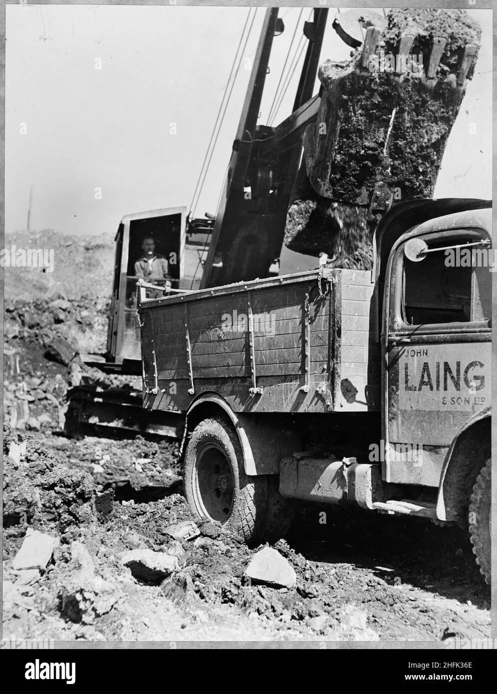 Filton Airfield, South Gloucestershire, 30/04/1950. Un escavatore dragline che deposita materiale da una benna in un furgone a pianale durante la costruzione di una nuova pista a Filton Airfield. Laing ha esteso la pista in direzione ovest a Filton Airfield per ospitare il liner Bristol Brabazon, che è stato costruito al campo d'aviazione. I lavori iniziarono nel luglio 1946 sulla nuova pista, lunga 2.725 metri e larga 100 metri. Quasi 750.000 iarde cubiche di scavi, fino ad una profondità di 14 piedi, sono stati coinvolti nella preparazione del sito per la pista. Il lavoro richiedeva la necessità e la rimozione del male di Charlton Foto Stock