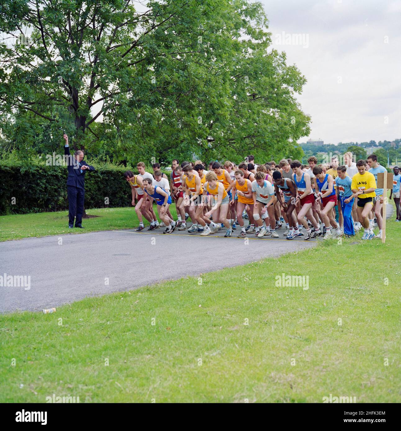 Copthall Stadium, Hendon, Barnet, Londra, 09/07/1988. I concorrenti partorono all'inizio di una gara su strada del 10km che si tiene al Copthall Stadium, con il presidente Martin Laing che spara la pistola di partenza. Questa gara su strada del 10km faceva parte di un evento di beneficenza tenutosi al Copthall Stadium il 9th luglio 1988, con l'obiettivo di raccogliere fondi per il Great Ormond Street Hospital Appeal. Hanno partecipato squadre di Laing provenienti da vari dipartimenti di tutto il paese. Foto Stock