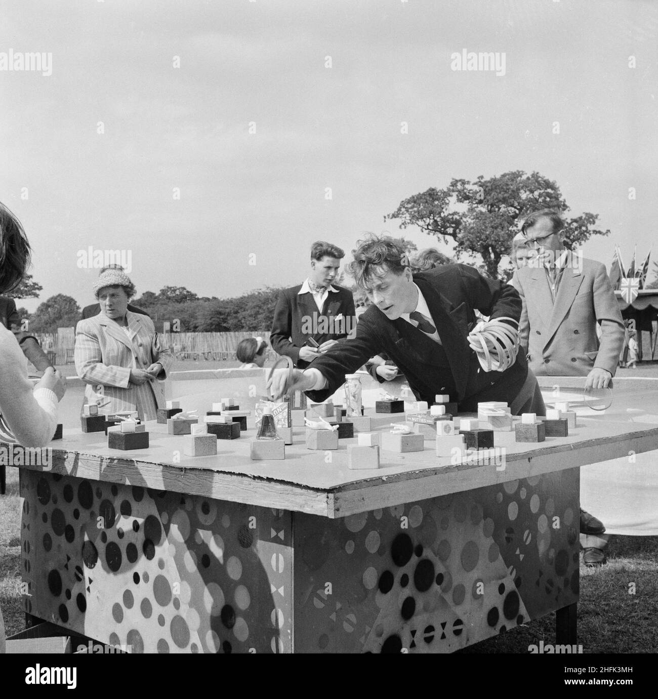 Laing Sports Ground, Rowley Lane, Elstree, Barnet, Londra, 30/06/1956. Persone che giocano al gioco 'hoopla' durante una giornata di sport Laing a Elstree, mostrando un tavolo con premi su piccoli blocchi e un uomo che raccoglie i cerchi pronti per il prossimo round. A questa giornata sportiva hanno partecipato molti membri del personale di Laing e le loro famiglie, alcuni dei quali si sono recati a Elstree da Swindon, Leicester e Dagenham. La giornata consisteva in vari eventi su pista e campo, nonché attrazioni per i bambini, tra cui giostre e artisti. Anche i concorsi di artigianato, cucina, fiori e fotografia erano lui Foto Stock