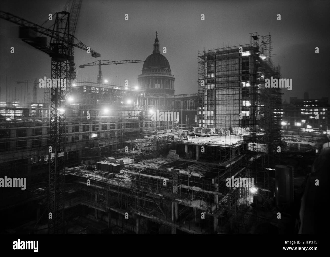 Paternoster Square, City of London, 14/01/1963. Una vista notturna a sud-est sullo sviluppo del Paternoster, che mostra il sito durante i lavori di costruzione con la Cattedrale di San Paolo sullo sfondo. I lavori sullo sviluppo di Paternoster sono stati condotti in una joint venture da John Laing Construction Limited, Trollope and Colls Limited e George Wimpey and Company Limited. Lo schema prevedeva la riqualificazione di un sito di sette acri sul lato nord della Cattedrale di St Paul&#x2019. Il sito era stato quasi interamente devastato durante un raid incendiario nel dicembre 1940. Lo sviluppo consisteva in o Foto Stock