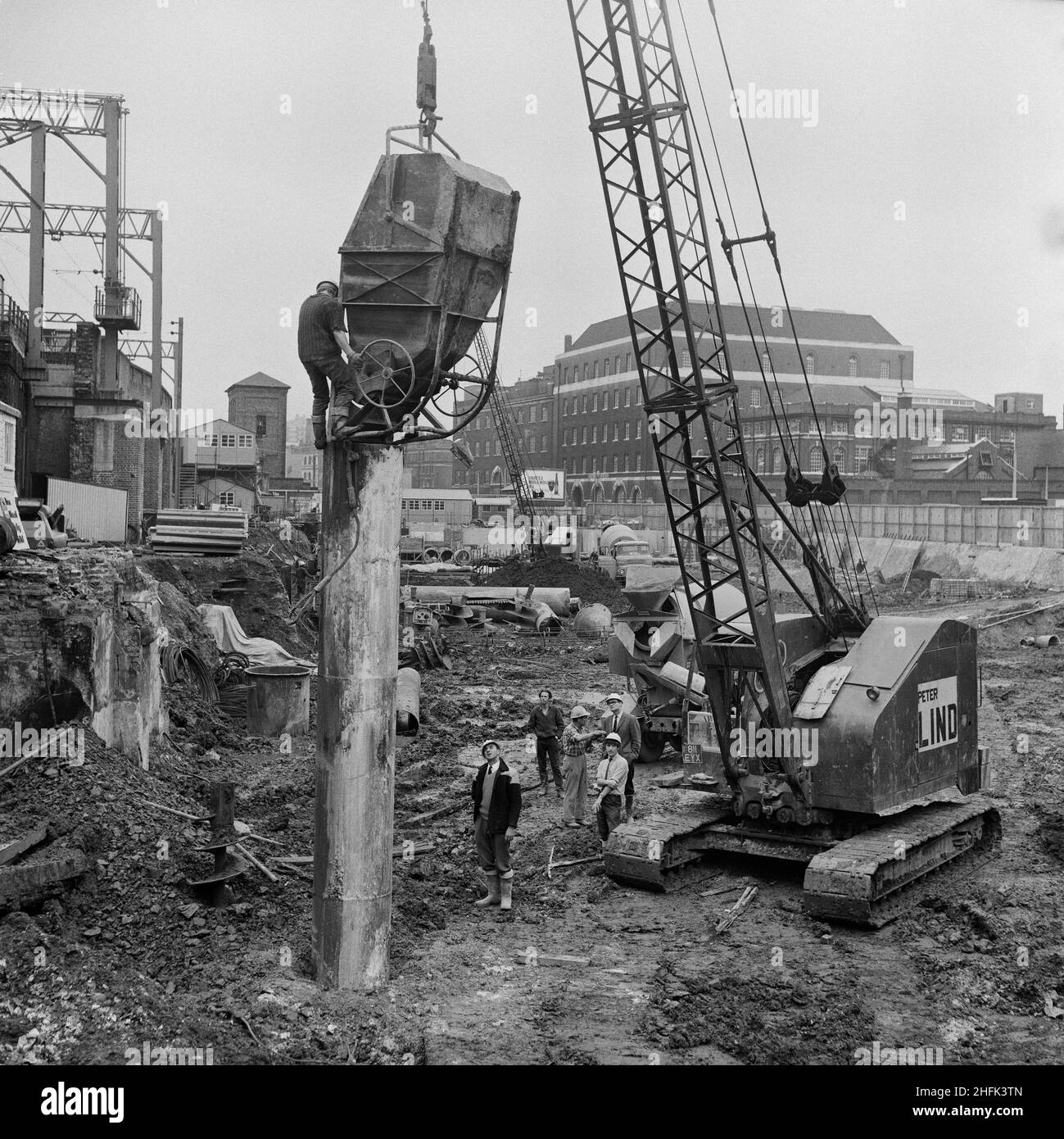 Minories Car Park, 1 Shorter Street, City of London, 11/10/1968. Un lavoratore che si trova in piedi sulla sommità di una colonna tubolare di acciaio e che lo riempie di calcestruzzo da una tramoggia sollevata da una gru presso il Minories Car Park. Foto Stock