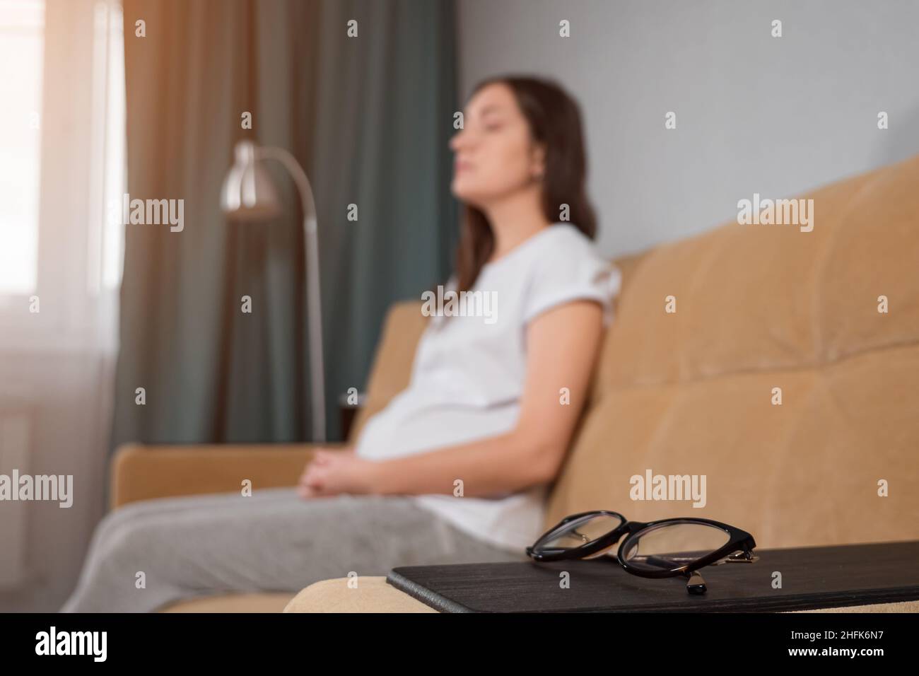 La donna con la vista povera cerca di trovare gli occhiali che toccano il divano Foto Stock