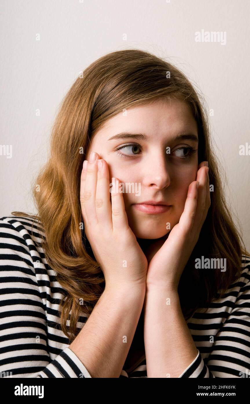 ritratto di una ragazza di tween guardando lateralmente, mani sul suo volto Foto Stock