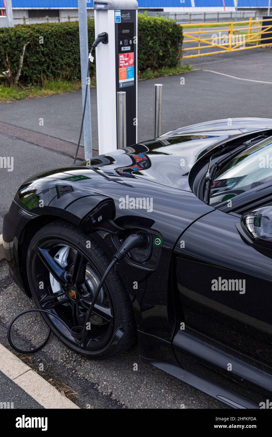Porsche Taycan 4S auto elettrica collegata a un punto di ricarica nel parcheggio NEC, Birmingham, Inghilterra Foto Stock