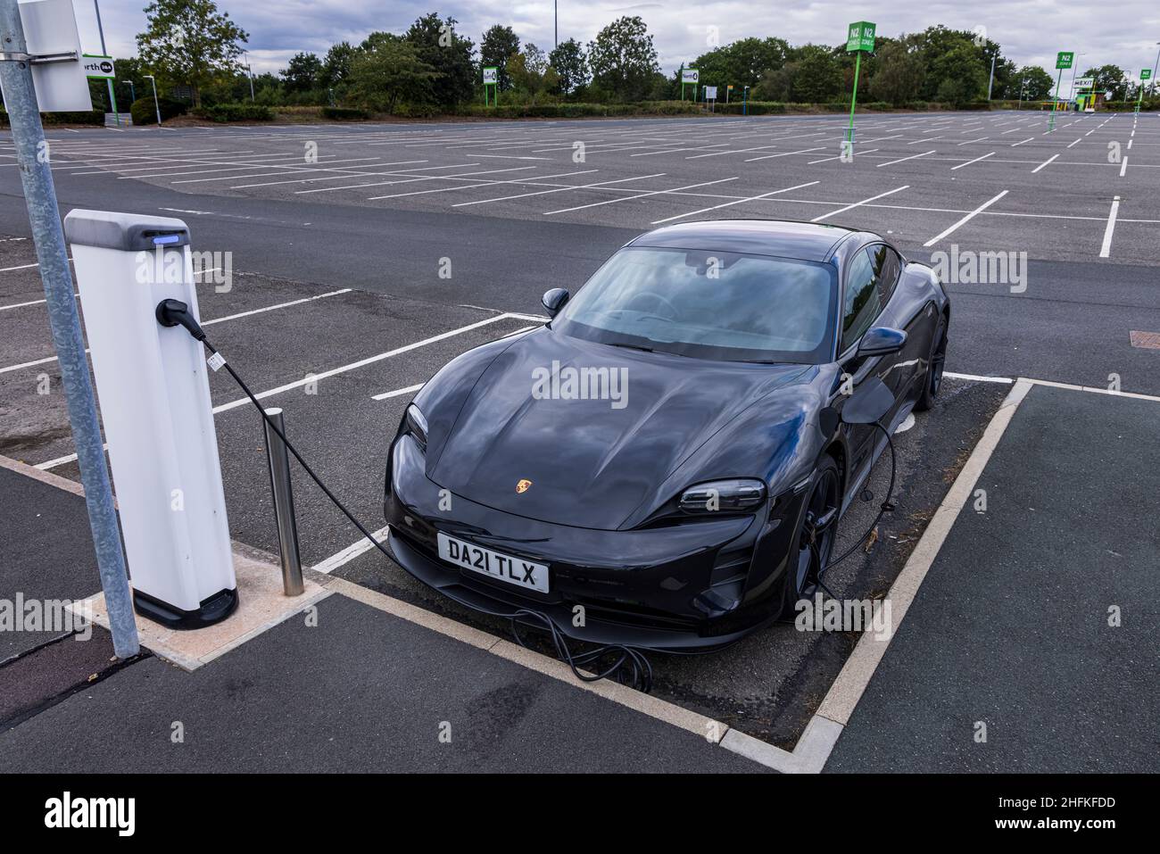 Porsche Taycan 4S auto elettrica collegata a un punto di ricarica nel parcheggio NEC, Birmingham, Inghilterra Foto Stock