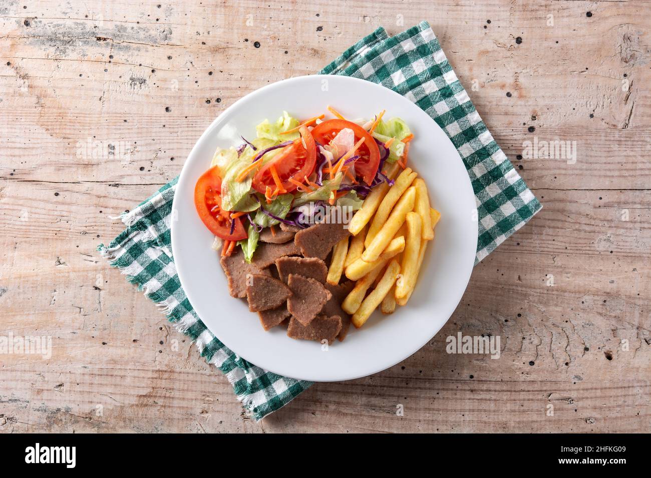 Piatto di kebab, verdure e patatine fritte su tavola di legno Foto Stock
