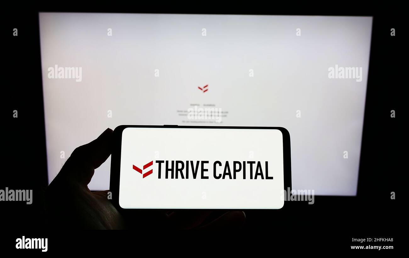 Persona che tiene smartphone con il logo della società statunitense THRIVE Capital Management LLC sullo schermo di fronte al sito web. Mettere a fuoco sul display del telefono. Foto Stock