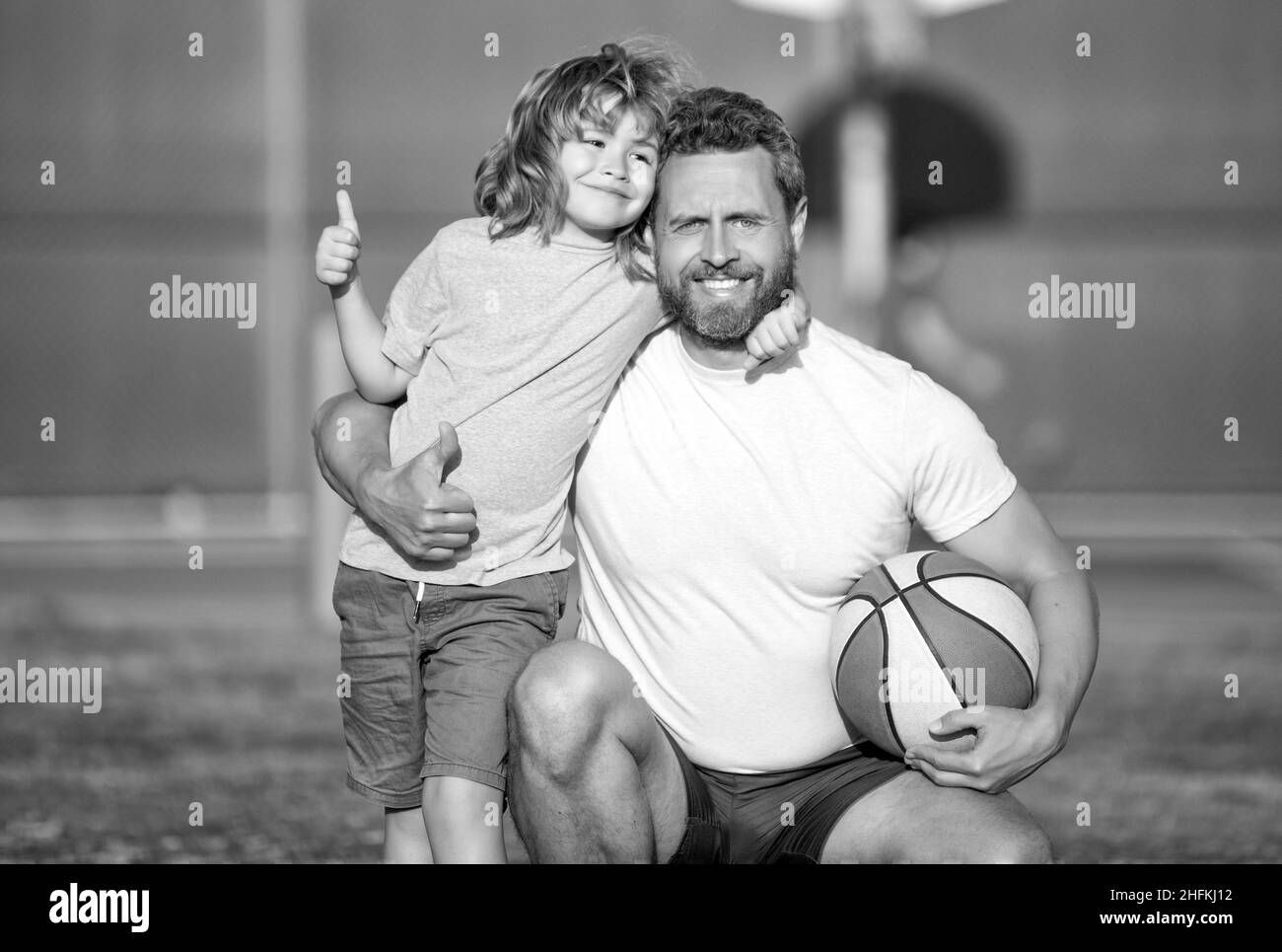 felice padre e figlio che gioca a basket con palla all'aperto, paternità Foto Stock