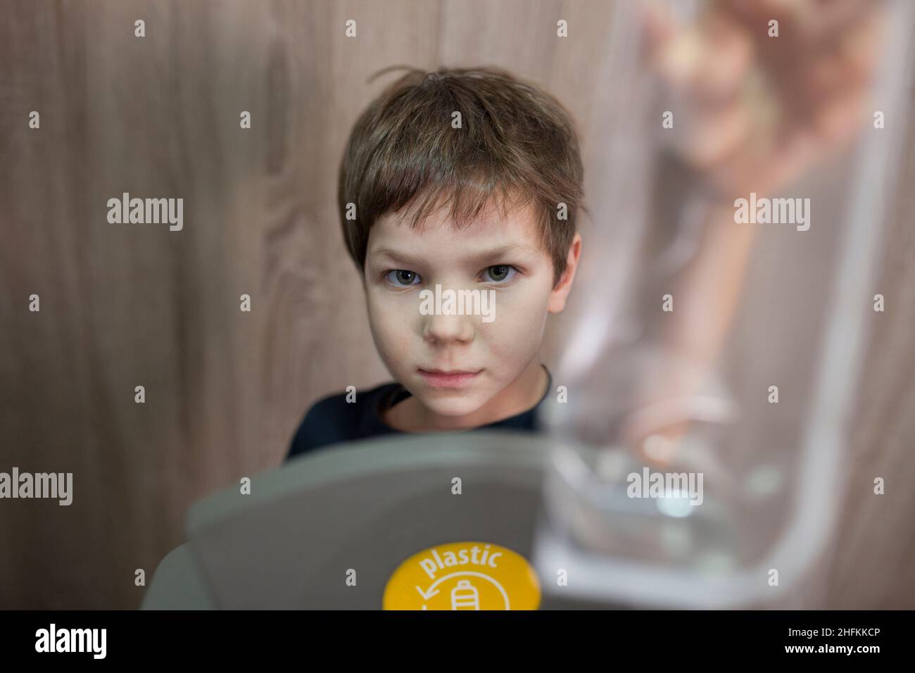 Bambino ragazzo gettando contenitore di cibo morbido per lo spreco di bidone per la plastica a casa. Formazione sul concetto di segregazione dei rifiuti Foto Stock