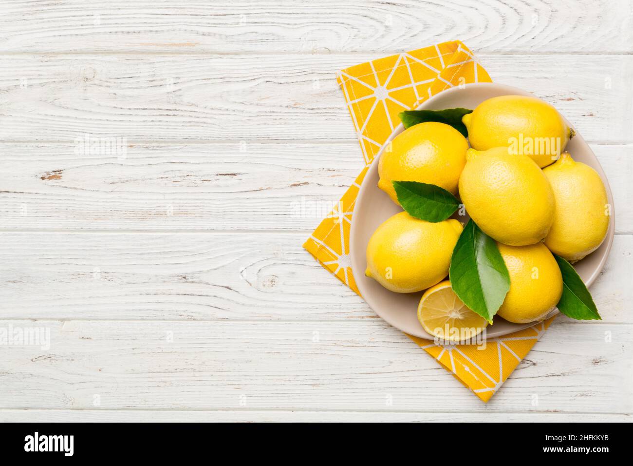 Limone tagliato fresco e limoni interi su piatto rotondo su sfondo colorato. Cibo e bevande ingredienti preparazione. Tema di cibo sano vista dall'alto Vith c Foto Stock