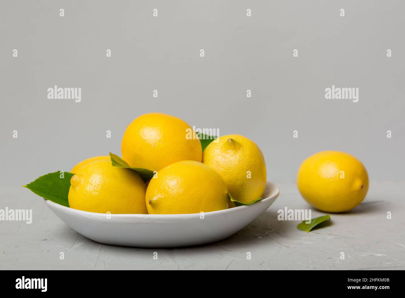 Limone tagliato fresco e limoni interi su piatto rotondo su sfondo colorato. Cibo e bevande ingredienti preparazione. Tema di cibo sano vista dall'alto Vith c Foto Stock