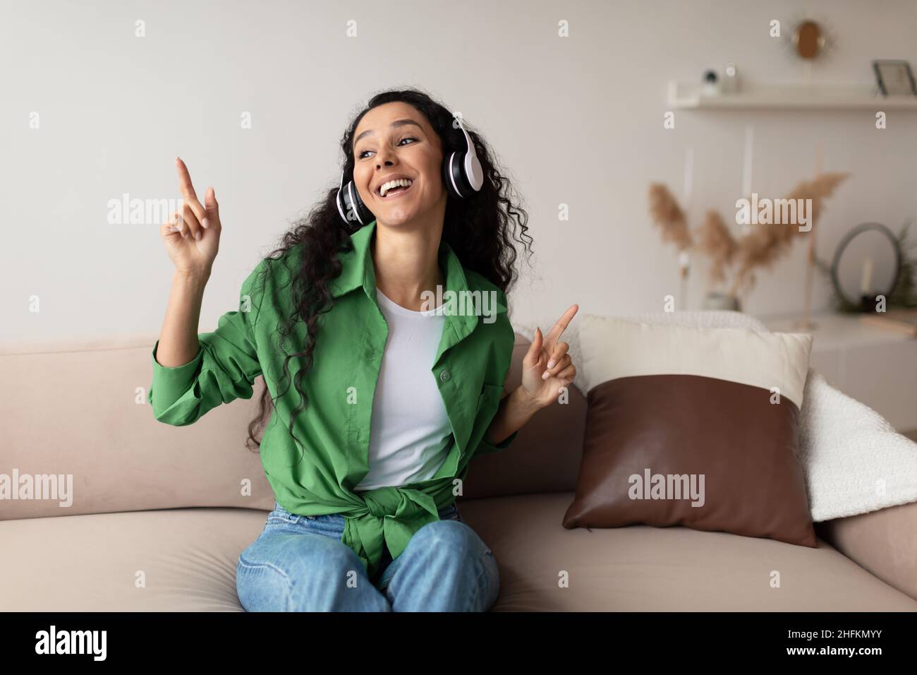 Middle Eastern Lady indossando cuffie che ascoltano musica a casa Foto Stock