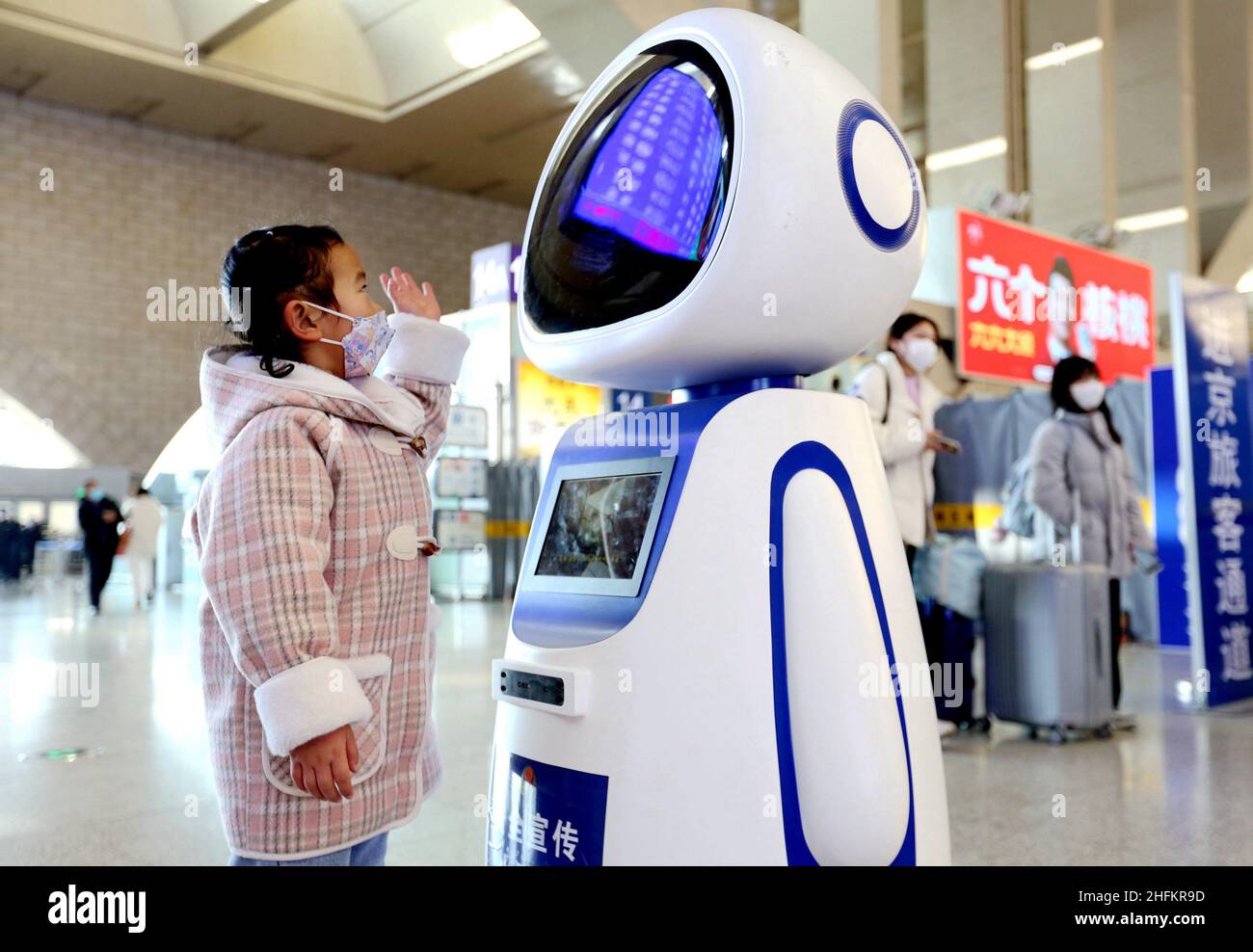(220117) -- SHIJIAZHUANG, 17 gennaio 2022 (Xinhua) -- Un bambino interagisce con un robot alla stazione ferroviaria di Shijiazhuang a Shijiazhuang, provincia di Hebei della Cina settentrionale, 17 gennaio 2022. Si prevede che la stagione di viaggio del Festival di primavera 2022 della Cina vedrà 1,18 miliardi di viaggi passeggeri, in aumento del 35,6% anno su anno, ma 20,3% inferiore a quello del 2020, ha detto il Ministero dei Trasporti. La stagione di viaggio di 40 giorni, nota anche come Chunyun, è iniziata lunedì e molte persone si reuniranno con le loro famiglie per il Capodanno lunare, o il Festival di primavera, che cade il 1 febbraio di quest'anno. (Xinhua/Yue noi Foto Stock