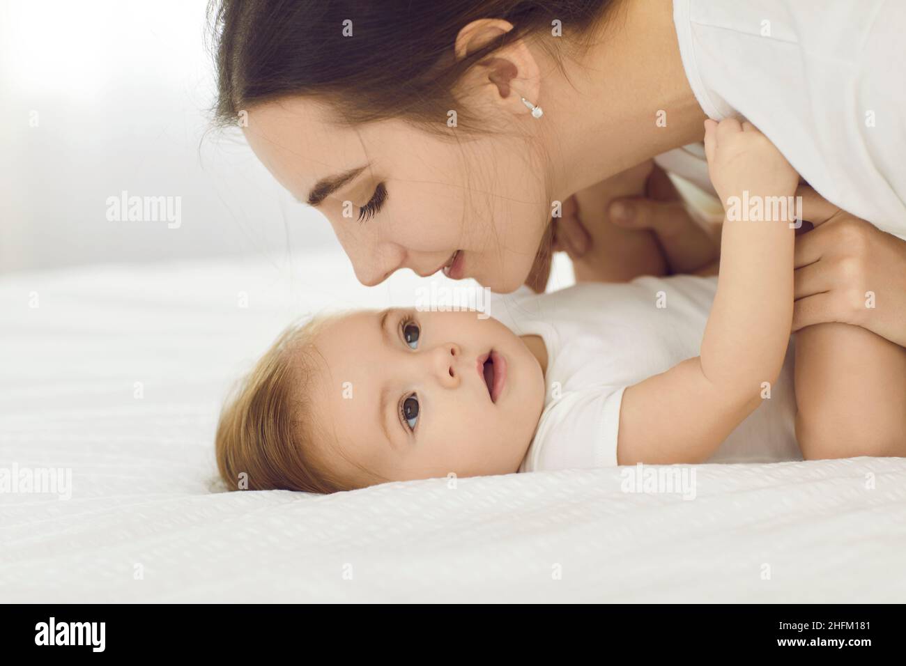 Amorevole giovane madre sta andando baciare il suo bambino guardandola con espressione di amore e tenerezza. Foto Stock