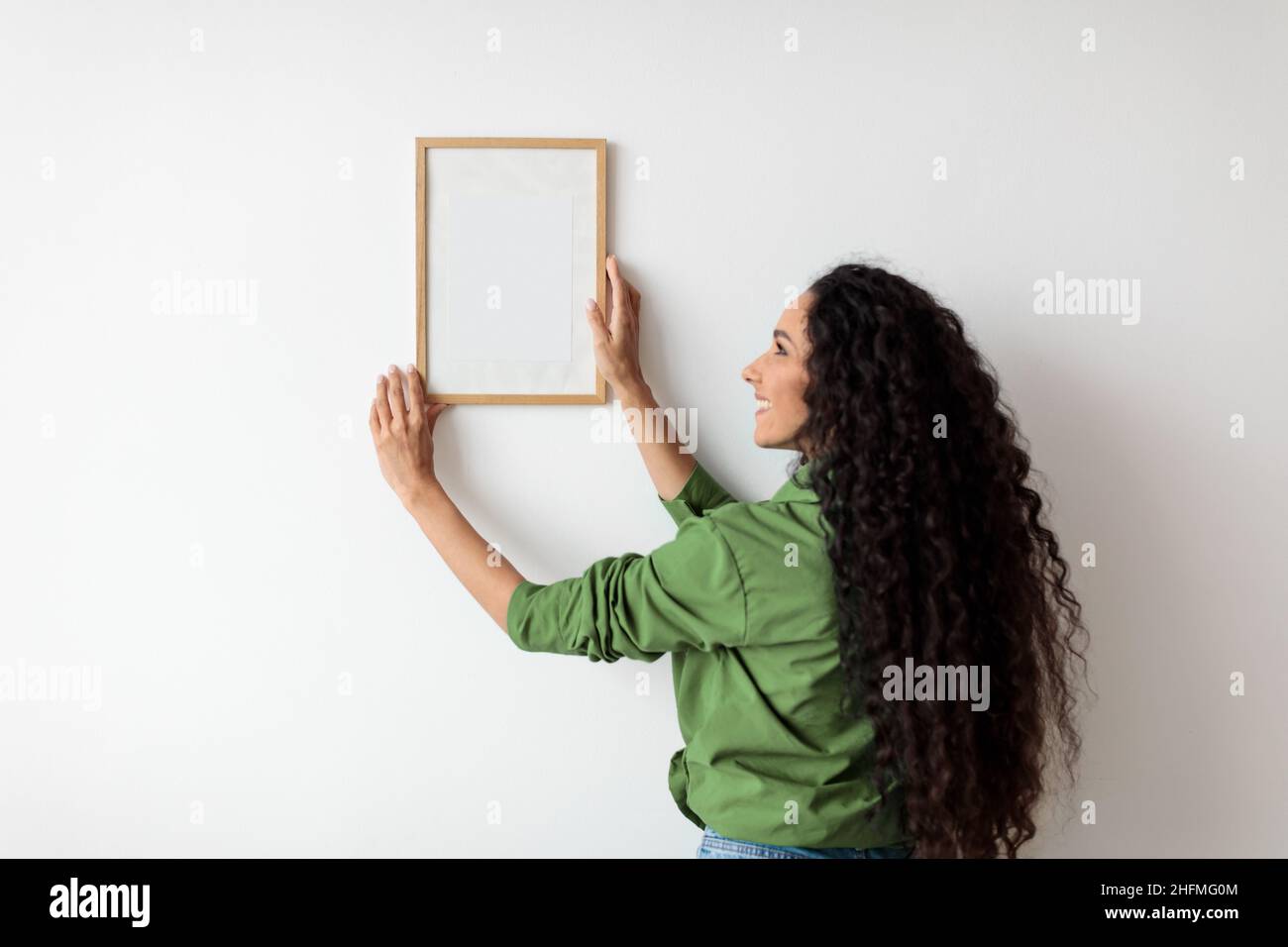 Lady Hanging Picture in Frame on Wall decorazione casa al chiuso Foto Stock