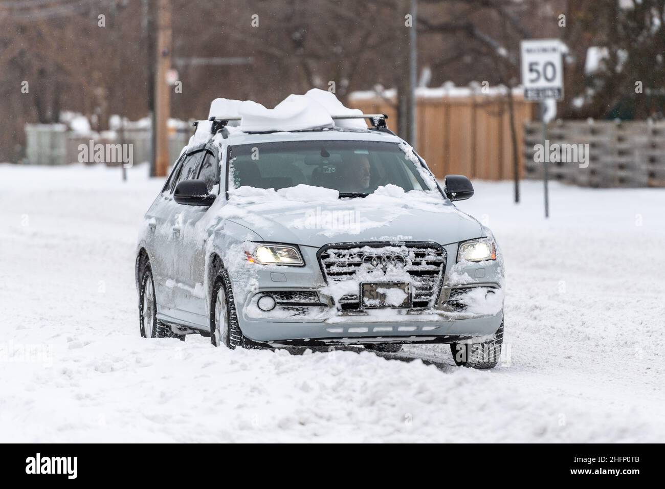 Un'auto Audi guida in Victoria Park Avenue con neve sul suo tetto. L'immagine mostra le condizioni di guida in una tempesta di neve invernale a Toronto, Canada Foto Stock