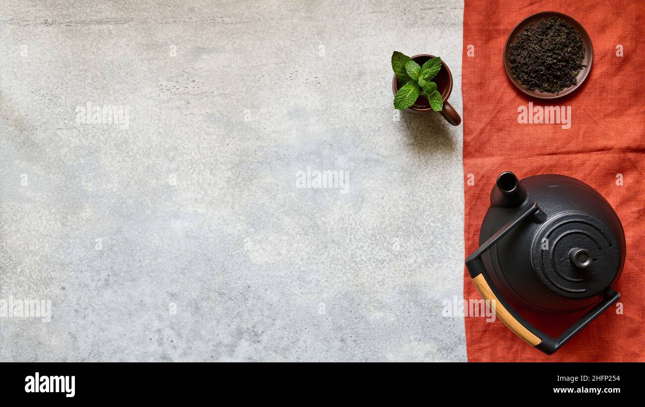 Teiera in ghisa, caffè e tazza con tè e foglie di menta su tovagliolo di lino, vista dall'alto con spazio per la copia Foto Stock
