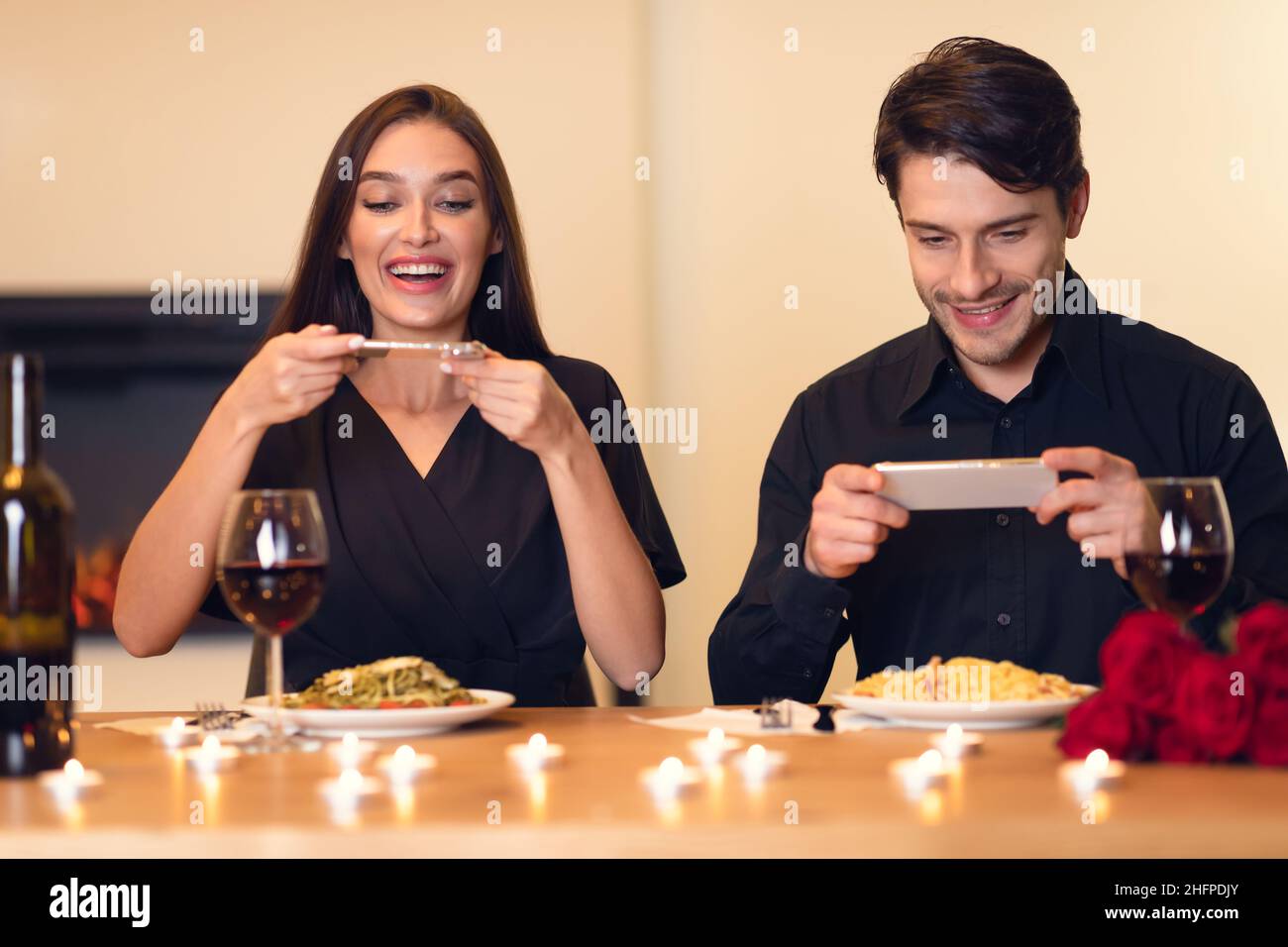 Ritratto di giovane coppia eccitata millennial seduta in ristorante e scattare foto di cibo con i telefoni cellulari per i social media, foodie blogger cel Foto Stock