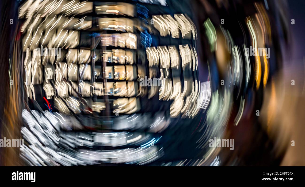 17 gennaio 2022, Hessen, Francoforte sul meno: Illuminate di sera sono ancora gli uffici in una delle torri della banca di Francoforte, che si trova accanto ad un grande cantiere. (Scatto con tempo di esposizione più lungo ed effetto di rotazione). Foto: Frank Rumpenhorst/dpa Foto Stock