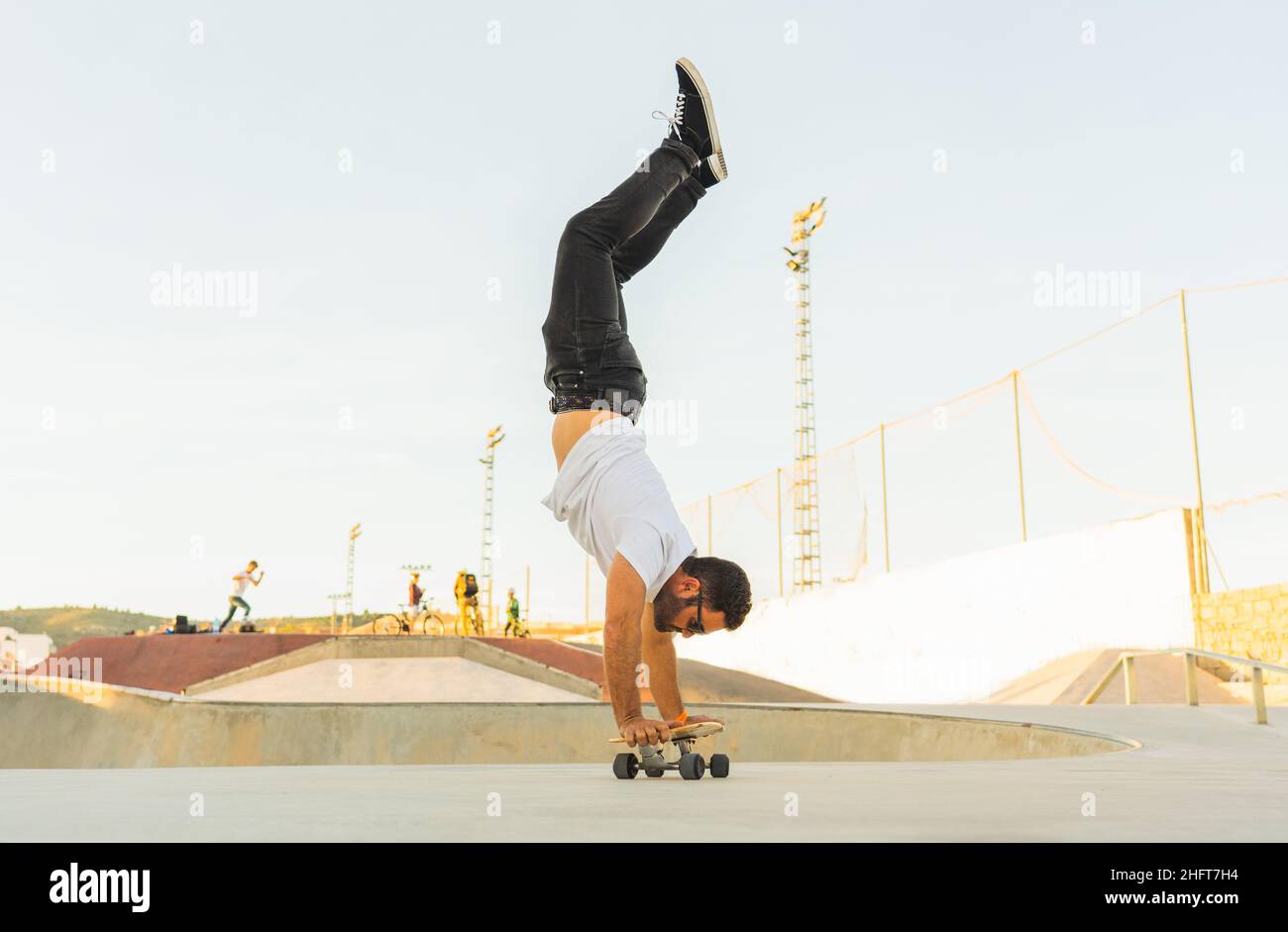 Uomo adulto che fa il trucco del pino con un surf di skate Foto Stock