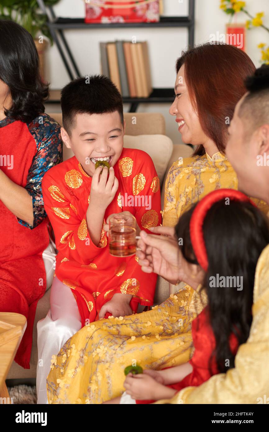 Ragazzo felice premedino godendo kiwi canditi con tè alla festa di Capodanno cinese della famiglia Foto Stock