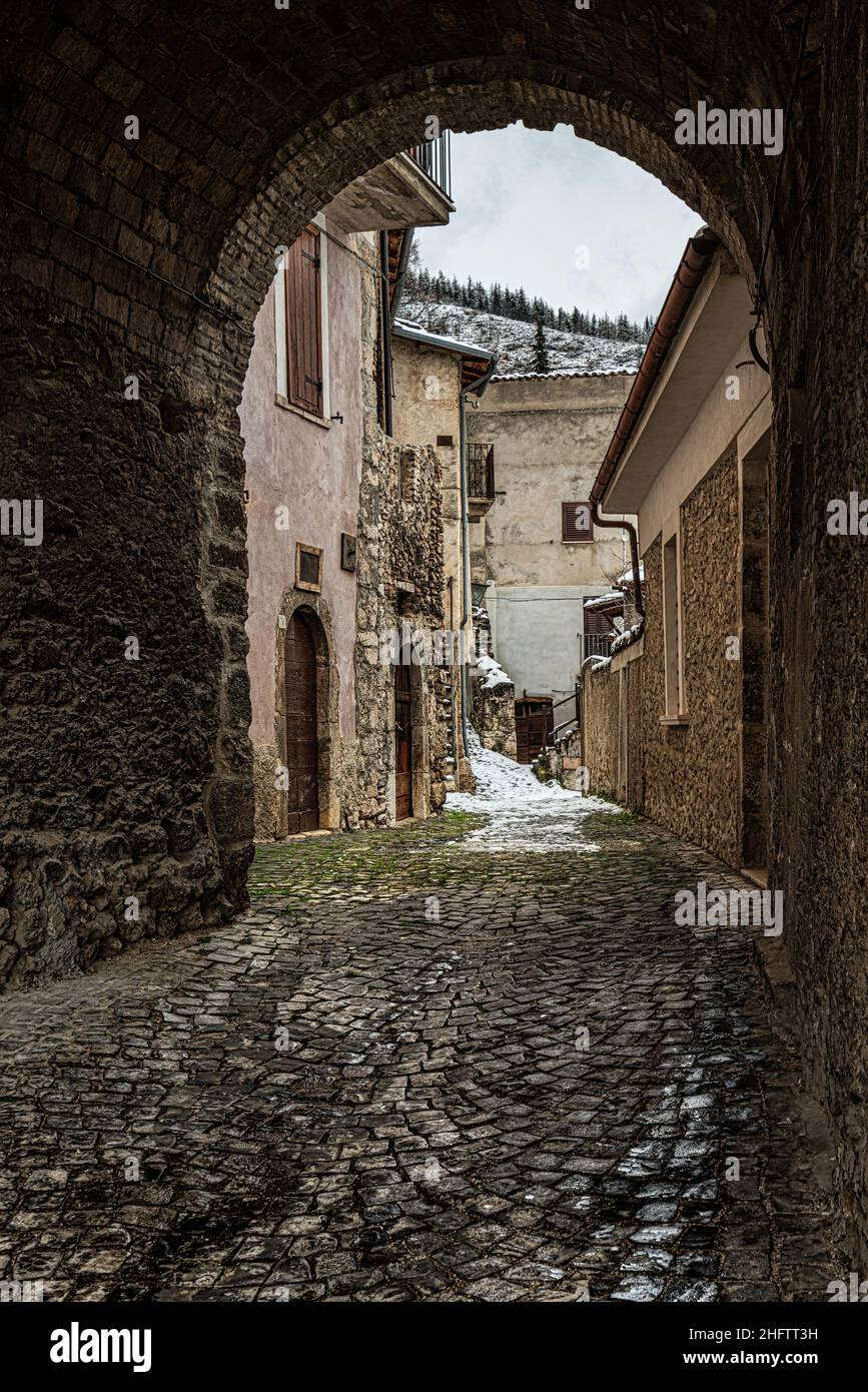 Arco di accesso con pavimento in ciottoli con vecchie case con neve. Provincia di l'Aquila, Abruzzo, Italia, Europa Foto Stock
