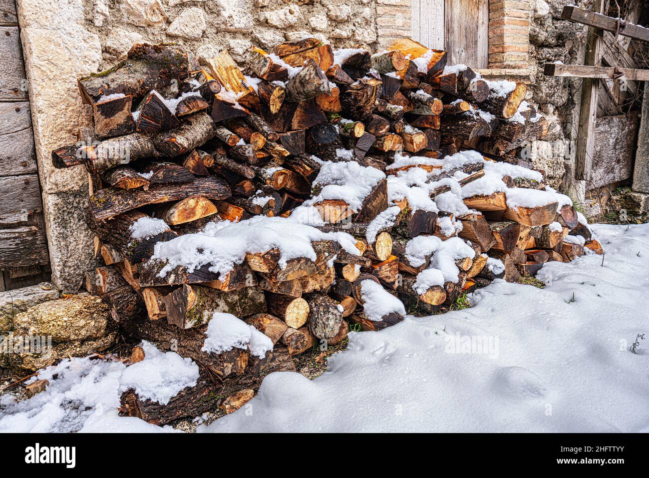 Legno tritato per il camino lasciato sotto la neve in una piccola città di montagna. Provincia di l'Aquila, Abruzzo, Italia, Europa Foto Stock