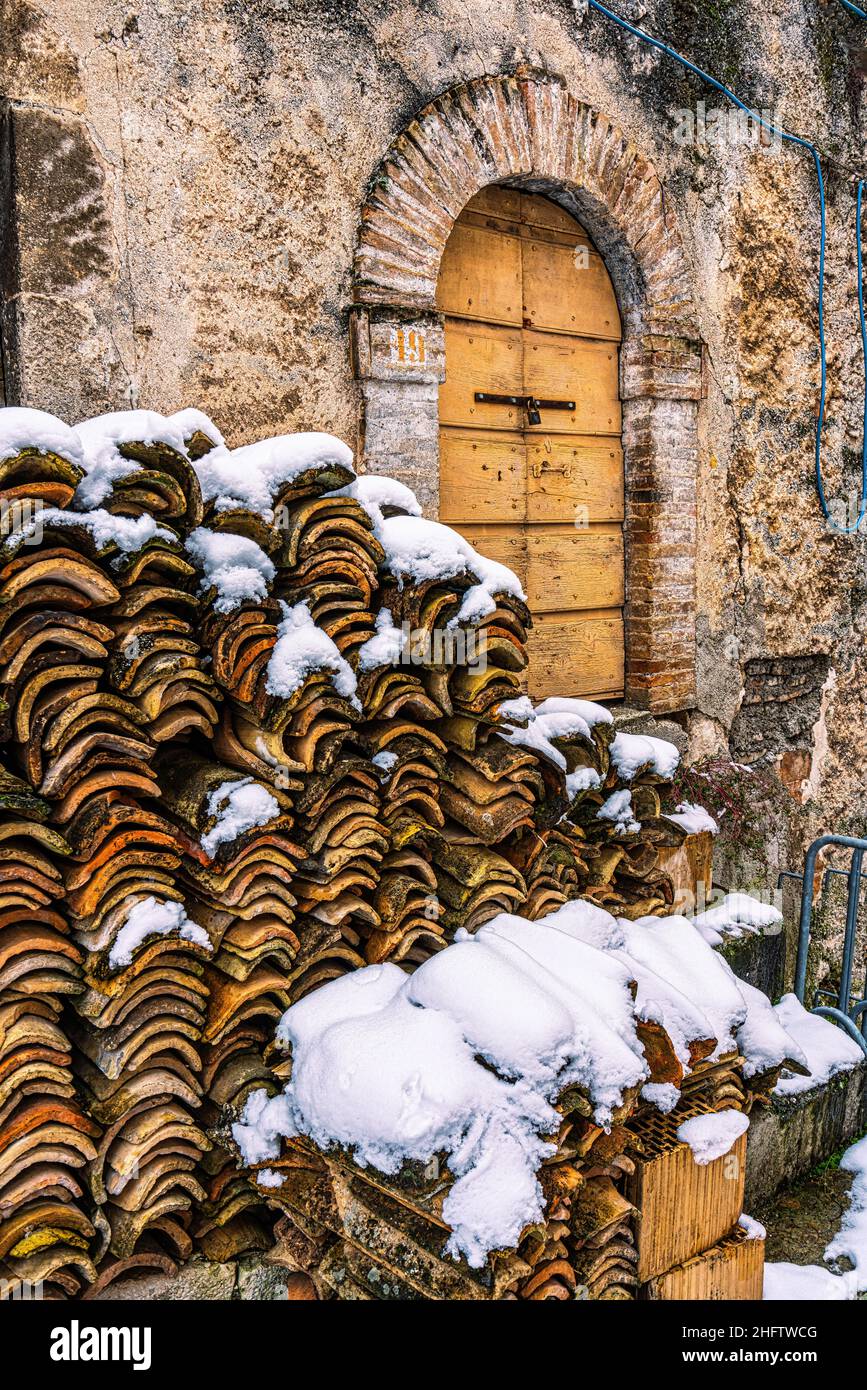 Vecchie mattonelle sotto la neve da utilizzare per il tetto di una vecchia casa nel piccolo paese montano di Secinaro. Secinaro, provincia di l'Aquila, Abruzzo Foto Stock