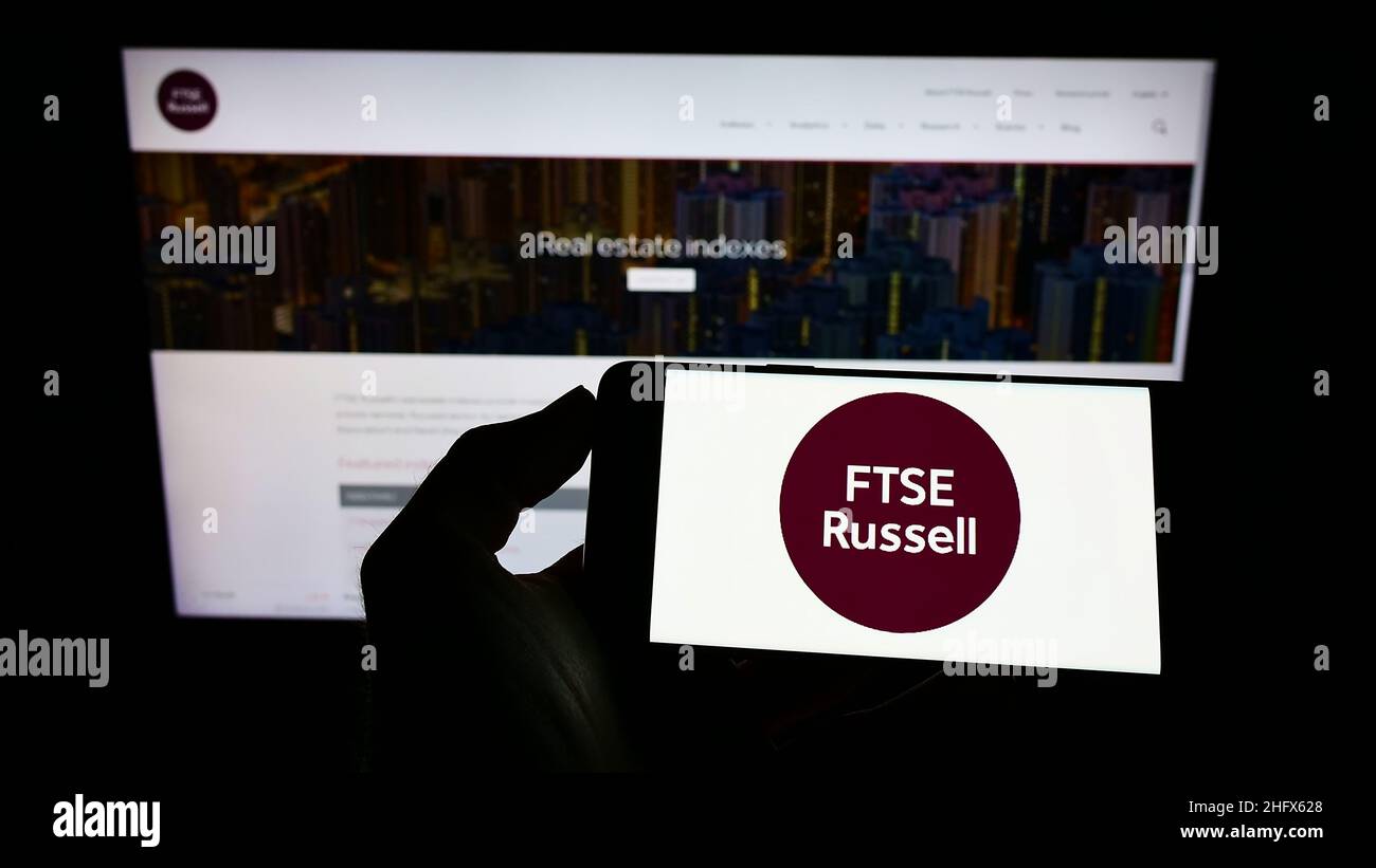 Persona che tiene il cellulare con il logo della società britannica FTSE Russell (LSEG) sullo schermo di fronte al sito web aziendale. Mettere a fuoco sul display del telefono. Foto Stock