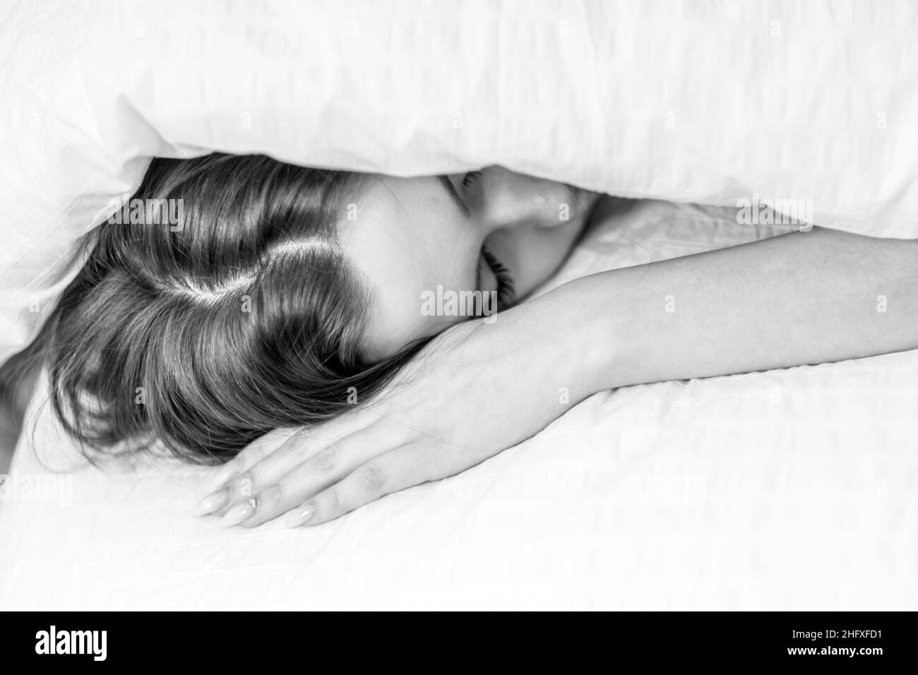 La donna si nascose sotto le coperte sul letto. Dormi sotto una coperta. Buona notte Foto Stock