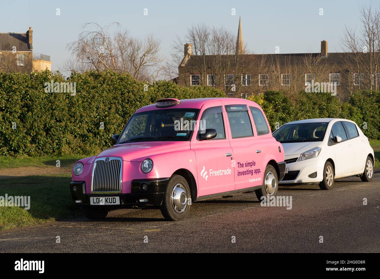 Vista frontale di tre quarti del taxi londinese dipinto con logo pubblicitario per Freetrade , la semplice app di investimento, visto nel villaggio di Blackheath Londra Inghilterra Foto Stock
