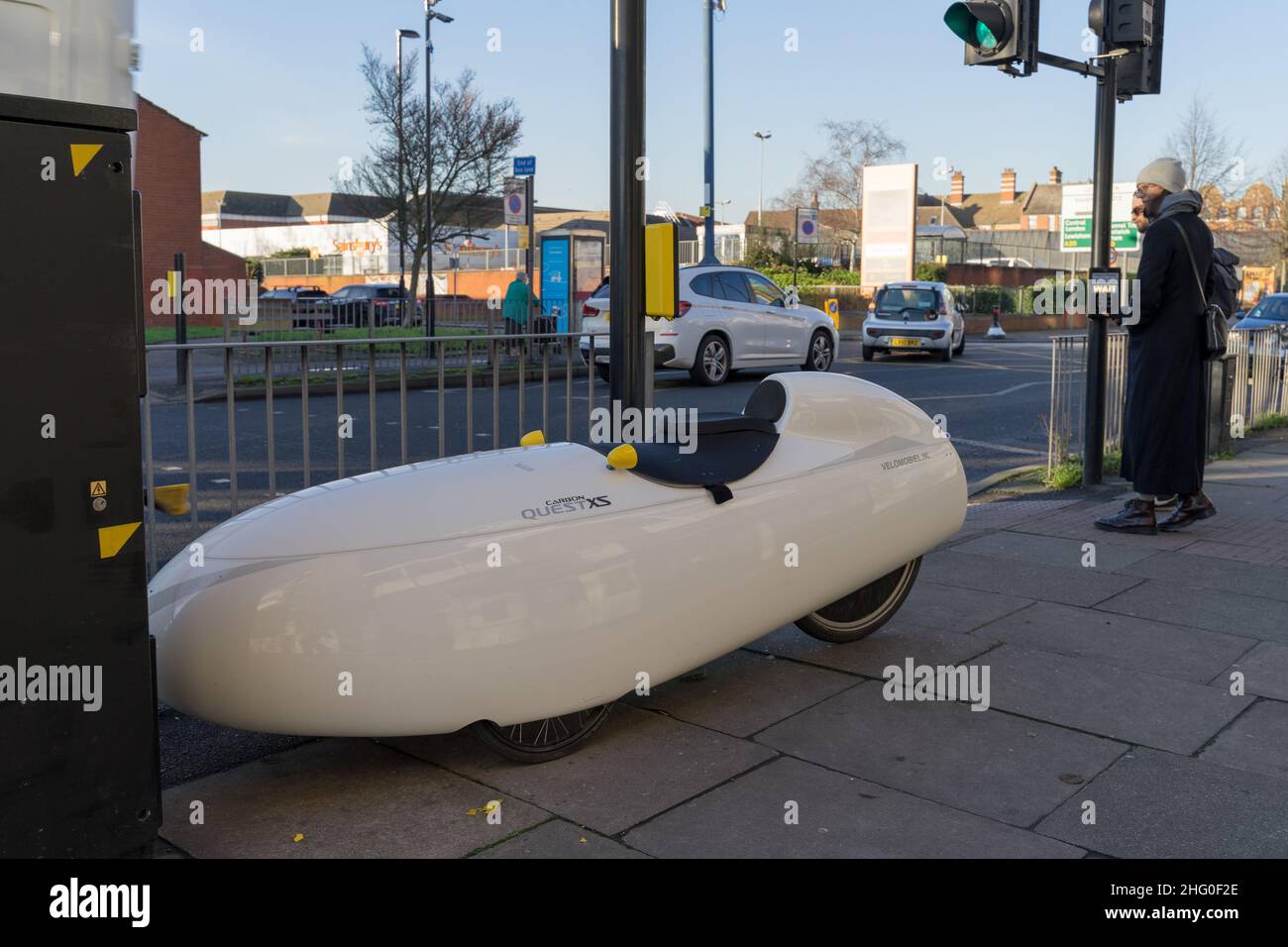 Quest XS Velomobiel , parcheggi auto pendolari accanto all'attraversamento pedonale, a Londra Greenwich Inghilterra Regno Unito Foto Stock