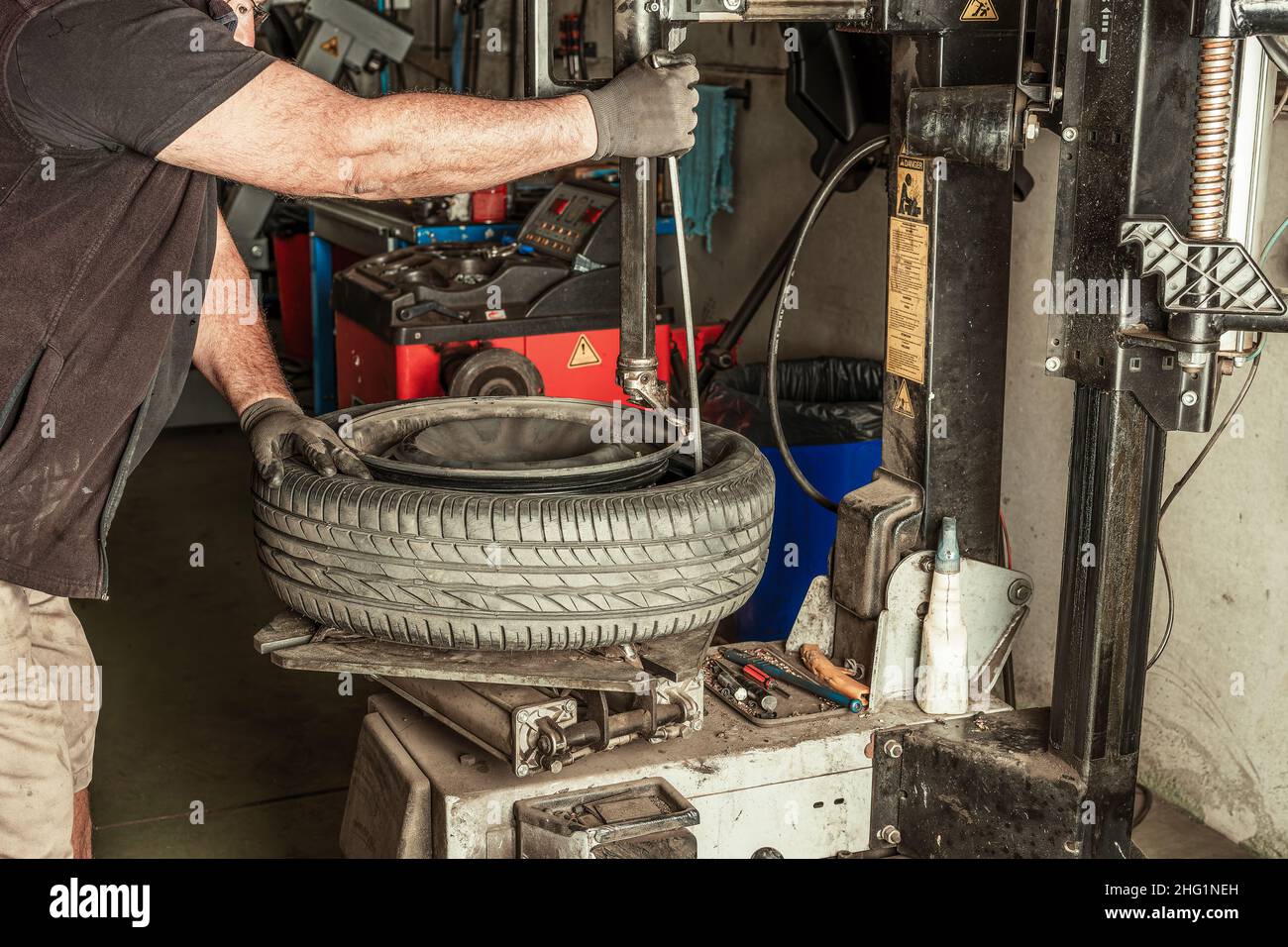 Il meccanico rimuove i cavi dalla ruota utilizzando attrezzi elettrici Foto Stock