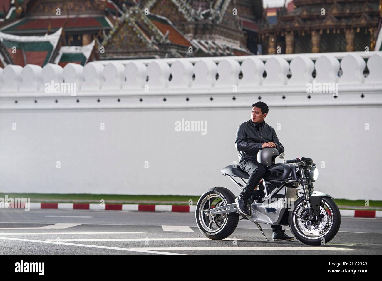 L'uomo si fermò con la sua moto elettrica al palazzo di Bangkok Foto Stock