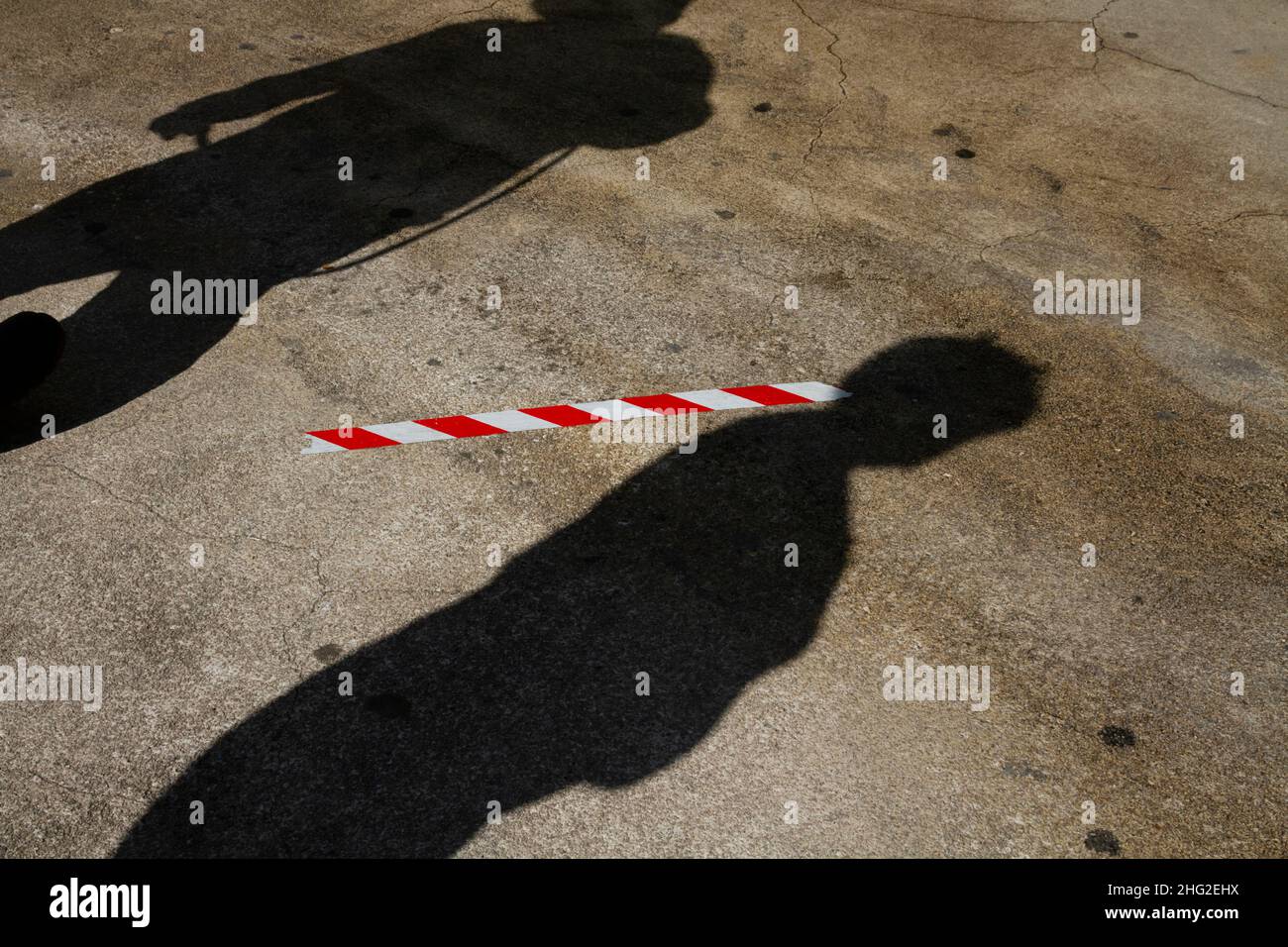 L'ombra di due persone sulla strada è separata da contrassegni di distanza sociale sull'asfalto per mantenere una distanza di sicurezza a causa del covid Foto Stock