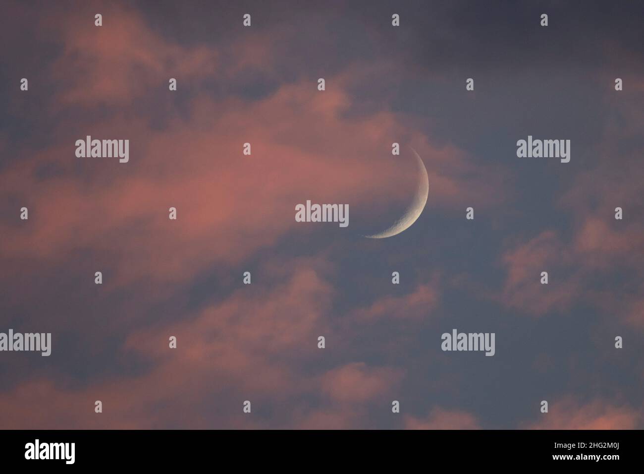Una luna crescente si estende attraverso le nuvole colorate sulla San Joaquin Valley della California. Foto Stock