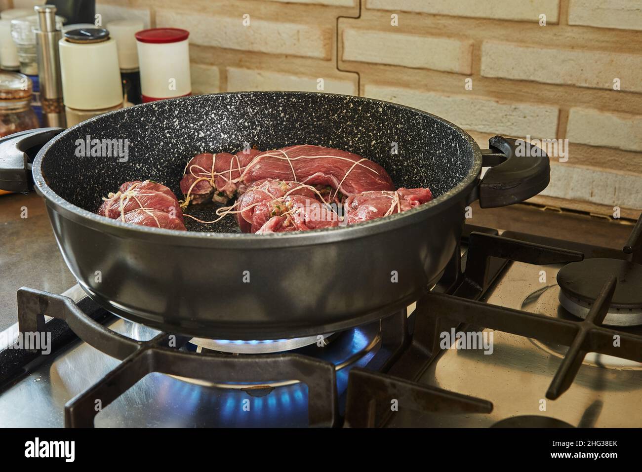 Lo chef frigge i panini di carne in una padella su una stufa a gas. Cucina gourmet francese Foto Stock
