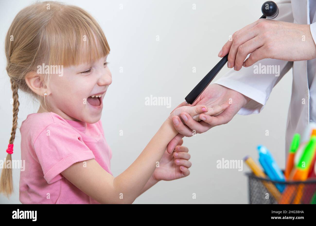 Medico neuropatologo controlla i riflessi nel palmo di una bambina caucasica di 5 anni Foto Stock