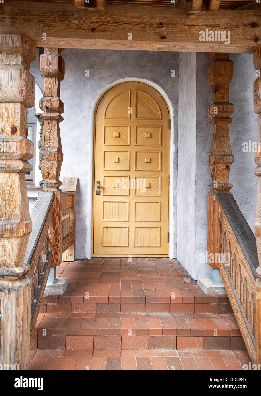 Porta semicircolare in legno nell'edificio d'ingresso e portico in pietra con gradini Foto Stock
