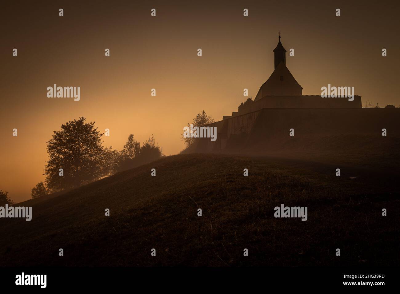 Cappella nella nebbia mattutina all'alba. alba. sole raggi all'alba. Foto Stock