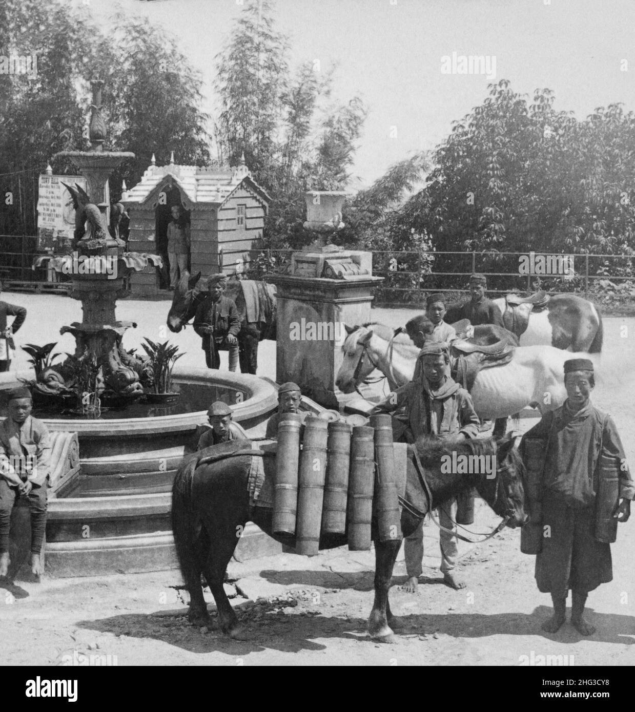 Foto d'epoca del milkman bhutanese con curiosi vasi di bambù, presso la fontana pubblica, Darjeeling, India. 1903 Foto Stock