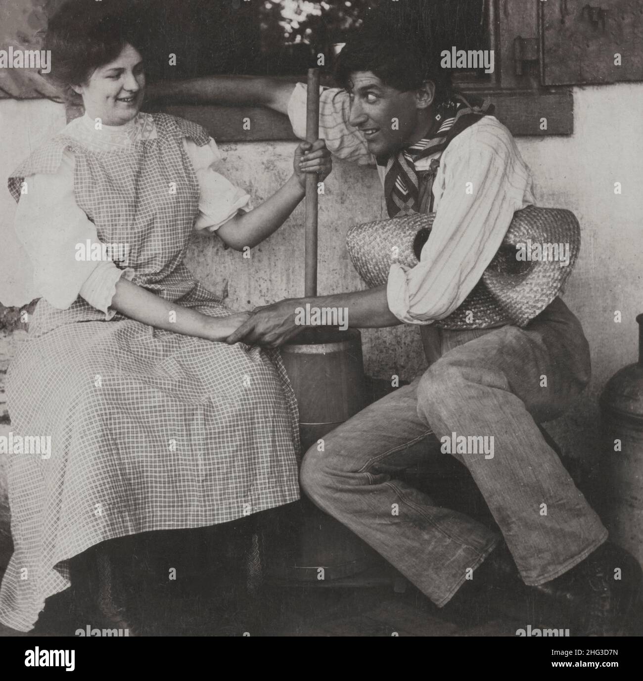 Vintage foto d'amore. Aspettate il latticello. USA. 1906 Farmer che tiene la mano di una donna che burba il burro. Foto Stock