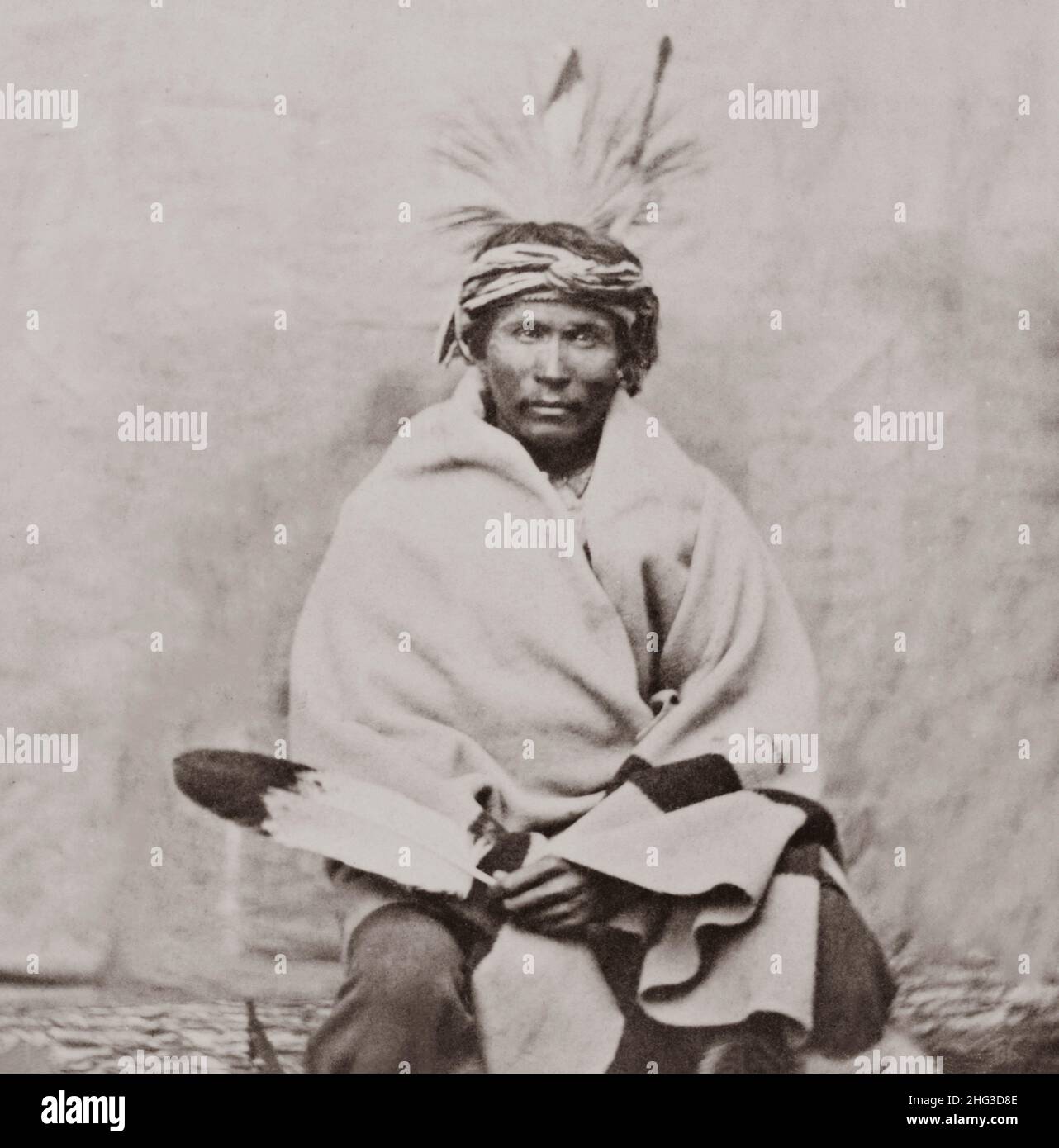 Foto d'epoca di Winnebago uomo, ritratto di tre quarti di lunghezza, fronte, seduta, avvolto in coperta. USA. 1868-1880 Foto Stock