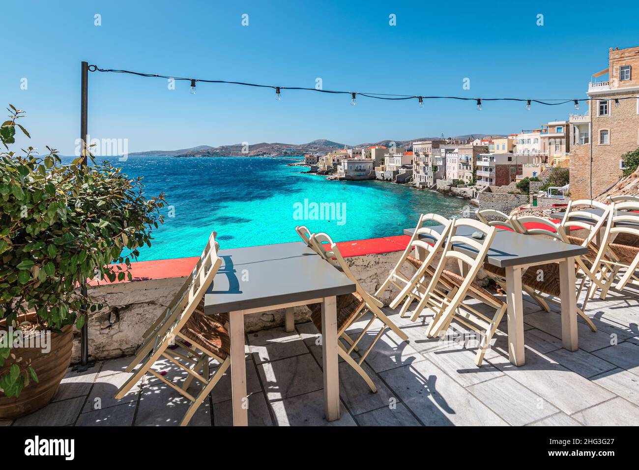 Sedie e tavoli vuoti di ristorante chiuso all'aperto con vista mare in Grecia. Foto Stock