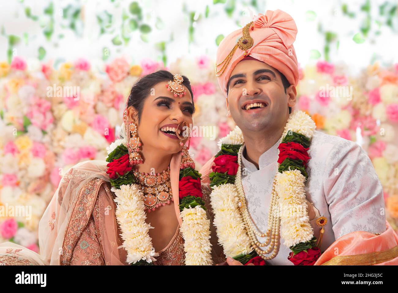 Ritratto di una felice coppia di nozze indiana seduta insieme su mandap Foto Stock