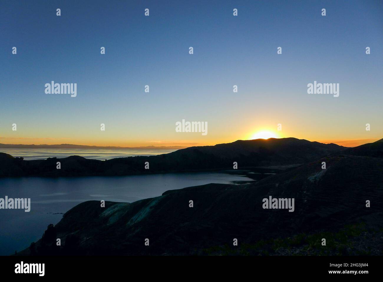 Bellissimo tramonto dietro la silhouette delle montagne sull'Isla del Sol con un cielo limpido e blu. Lago Titicaca - Bolivia Foto Stock