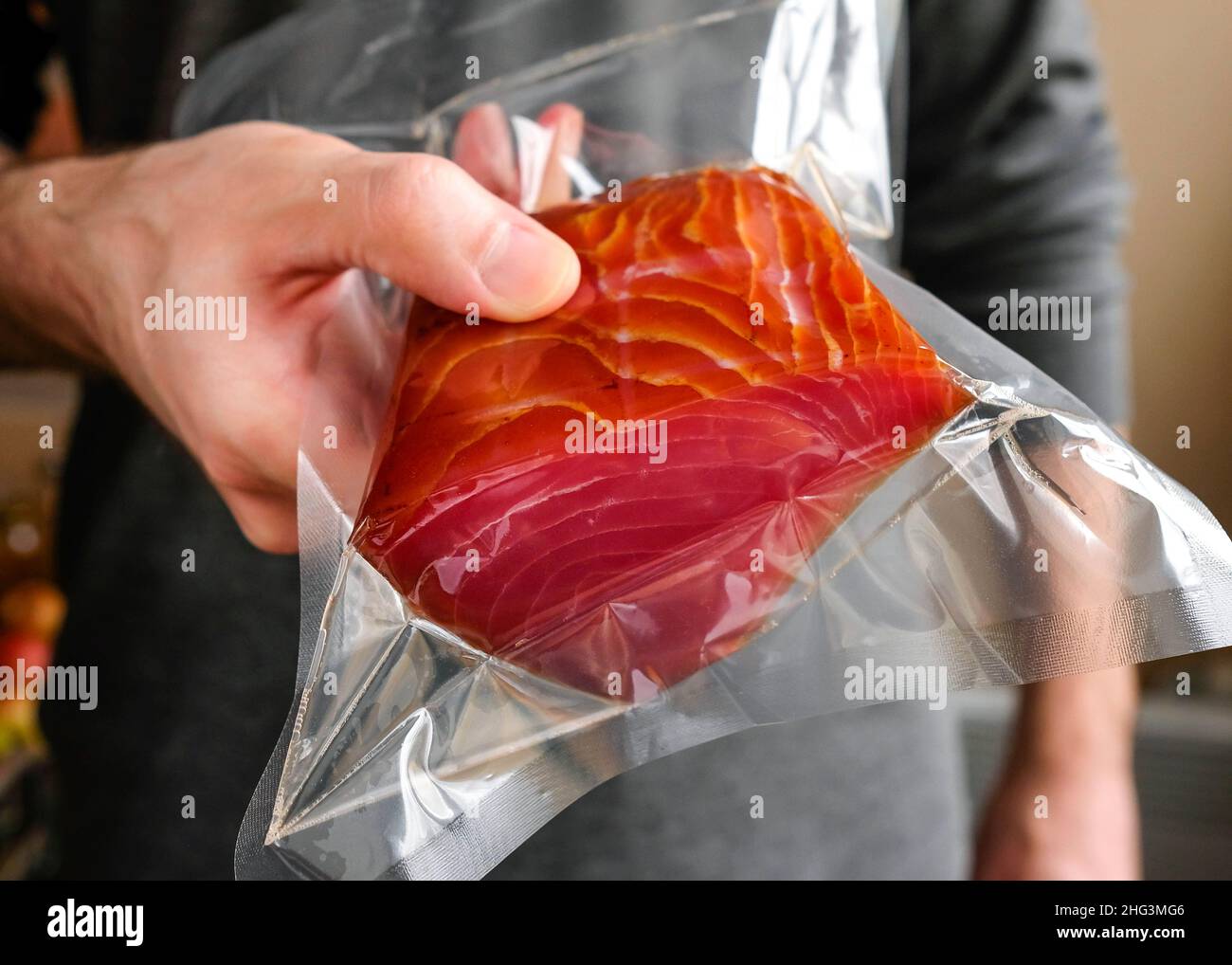 Un uomo che tiene un pesce rosso in un pacchetto. Foto Stock