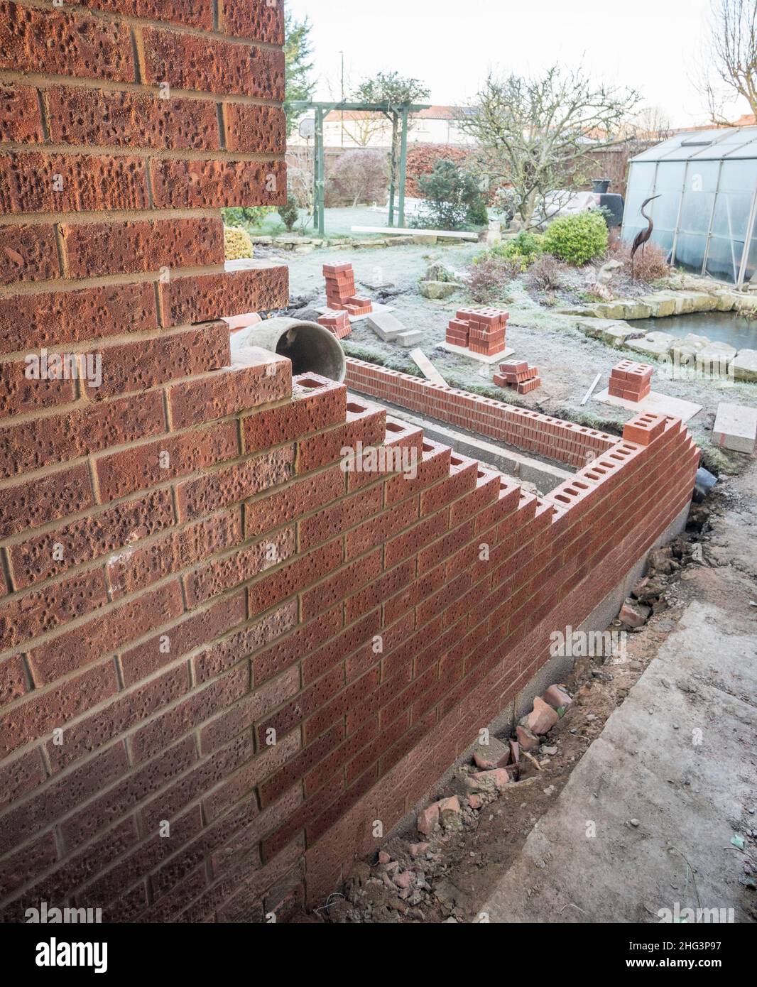 Estendendo un muro di mattoni facendo dei denti o utilizzando mattoni a incastro, Inghilterra, Regno Unito Foto Stock