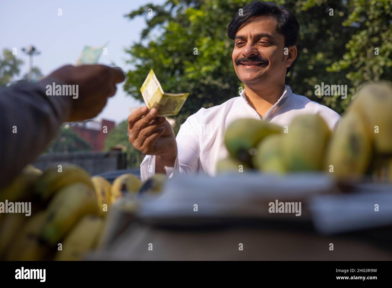 Uomo che dà soldi al venditore per banane nel mercato Foto Stock